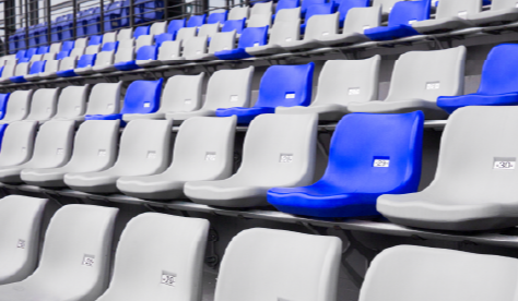 Sección de asientos numerados en un recinto deportivo moderno, con predominancia de asientos grises y algunos azules dispersos. Refleja el diseño contemporáneo y la innovación en la infraestructura de espacios deportivos.