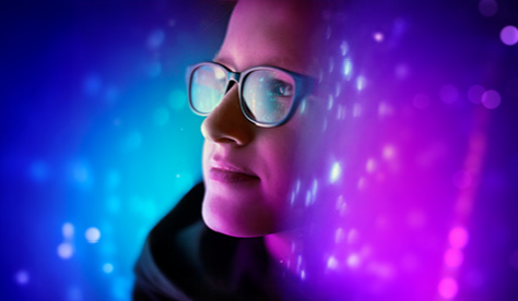 Fondo futurista con tonos azul y púrpura, patrones de luz abstractos y efectos bokeh. Al centro, una figura difusa representa la transformación y la innovación como motores clave de la competitividad empresarial.